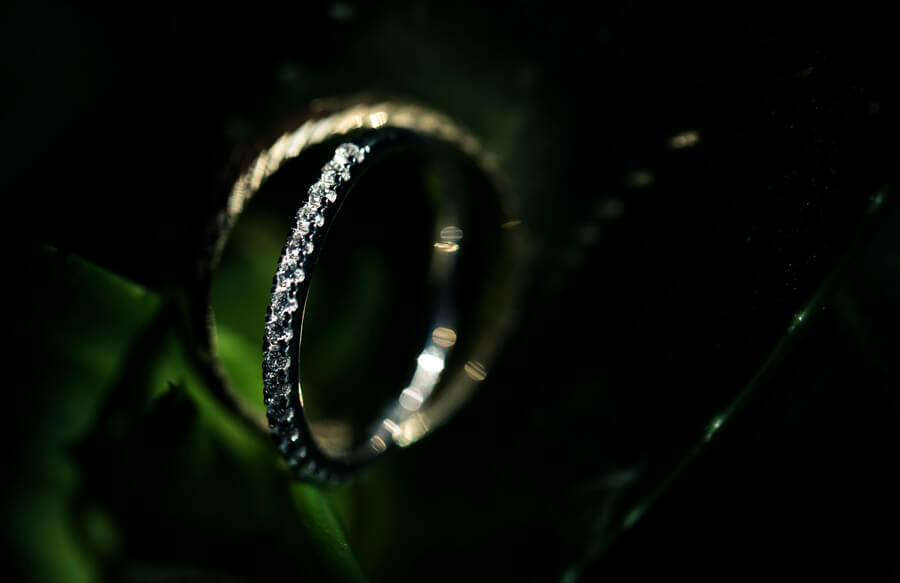photo d'alliances en or et diamants de futurs mariés dans des feuilles vertes